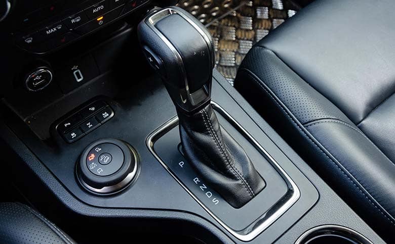 Cần số xe ô tô số tự động với các ký hiệu P, R, N, D và chế độ chuyển số tay, nằm trên bảng điều khiển trung tâm bọc da cao cấp.