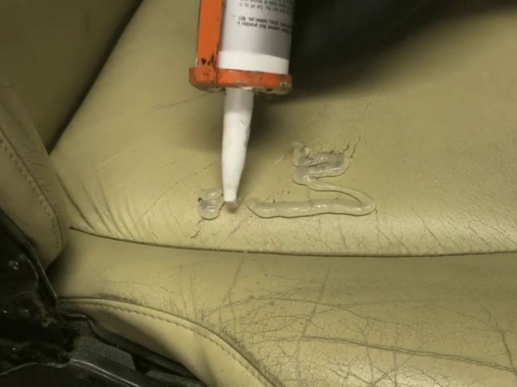 Thợ đang dùng keo trét vá vết rách trên ghế da màu kem