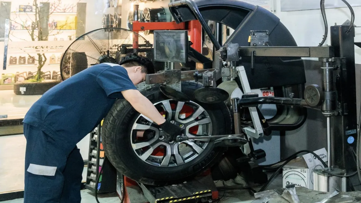 Kỹ thuật viên thực hiện cân bằng động lốp xe bằng máy chuyên dụng
