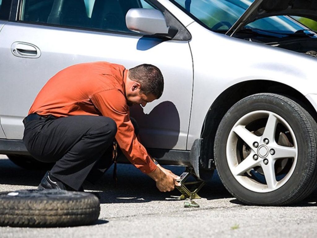Tài xế đang tự thay lốp xe giữa đường