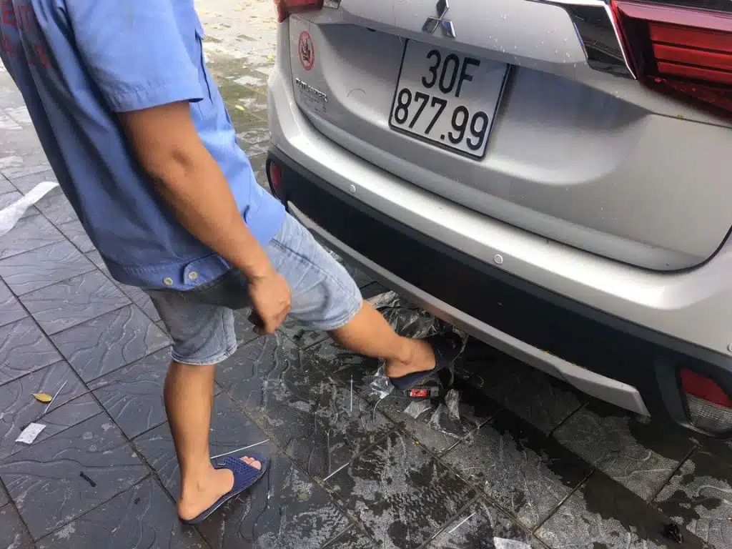 Kỹ thuật viên đang lắp đặt độ cảm biến đá cốp cho xe Mitsubishi Outlander, giúp mở cốp tự động tiện lợi mà không cần chạm tay.