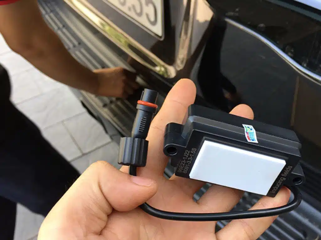 Cận cảnh bộ module độ cảm biến đá cốp đang được kỹ thuật viên kiểm tra và lắp đặt vào xe ô tô.