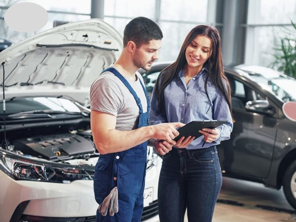 Nhân viên kỹ thuật tư vấn khách hàng về lắp đặt ghế chỉnh điện ô tô tại gara.