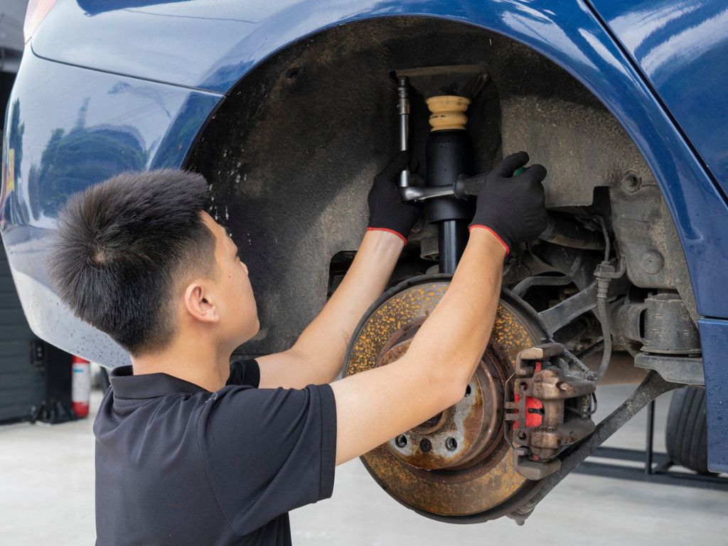 Thợ sửa chữa đang thay thế giảm xóc ô tô để đảm bảo khả năng vận hành ổn định của xe.