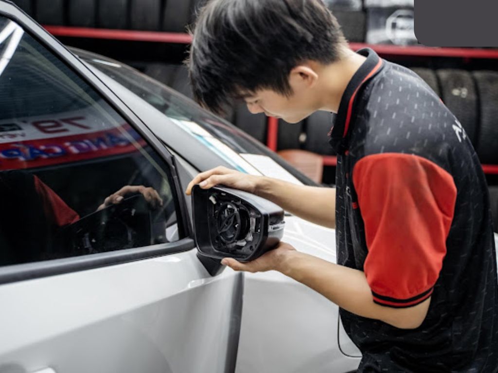 Kỹ thuật viên đang lắp đặt gương gập tự động cho ô tô tại gara chuyên nghiệp.