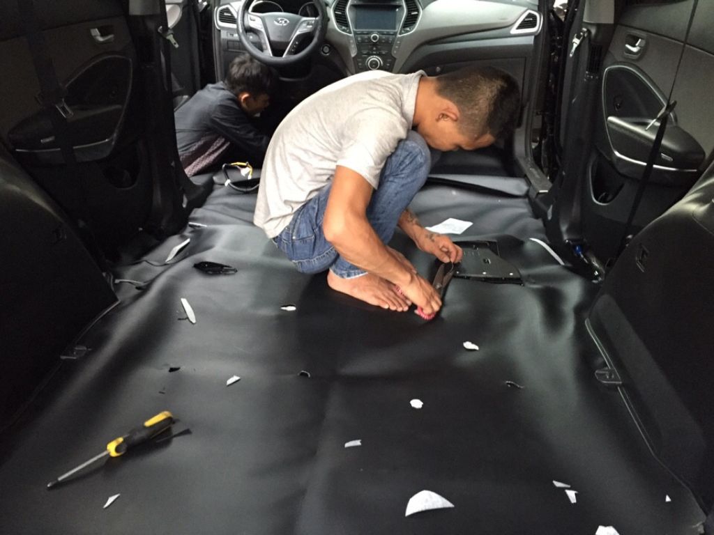 Thợ đang lắp đặt và căn chỉnh lót sàn Simili cho ô tô