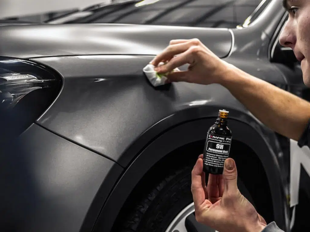 Kỹ thuật viên phủ nano và phủ ceramic lên bề mặt sơn ô tô màu xám bằng dung dịch bảo vệ 9H