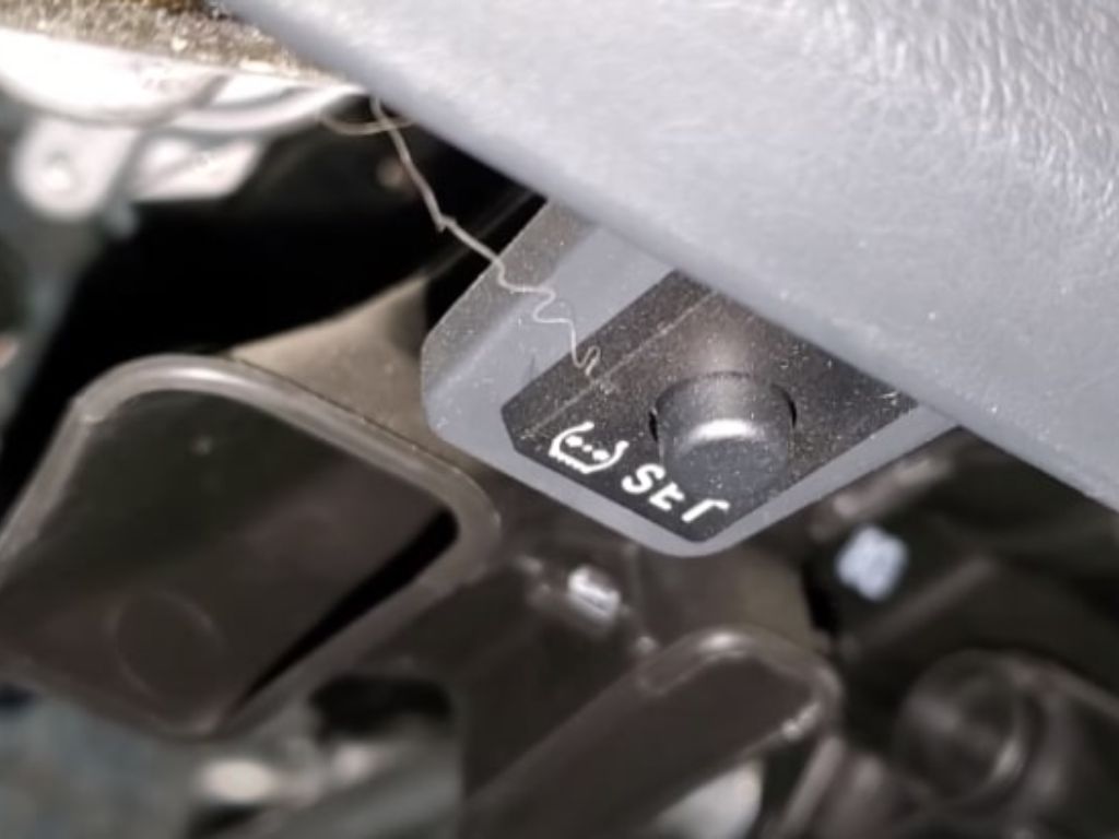 Nút reset cảm biến áp suất lốp nằm dưới bảng táp-lô xe, giúp người dùng tự cài lại cảm biến sau khi bơm lốp.