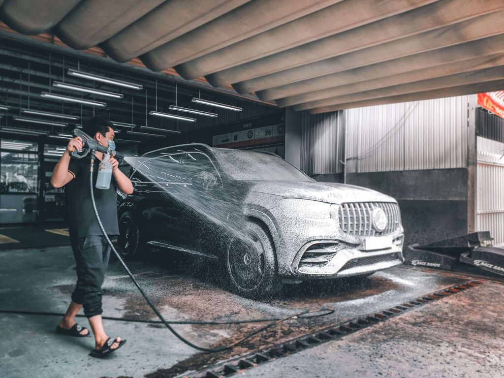 Kỹ thuật viên đang thực hiện quy trình rửa xe detailing với bọt tuyết phủ toàn thân xe Mercedes sang trọng.