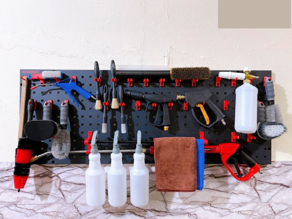 Bộ dụng cụ rửa xe detailing chuyên dụng gồm súng xịt, chổi mềm và khăn microfiber treo gọn gàng trong tiệm VinaWash.