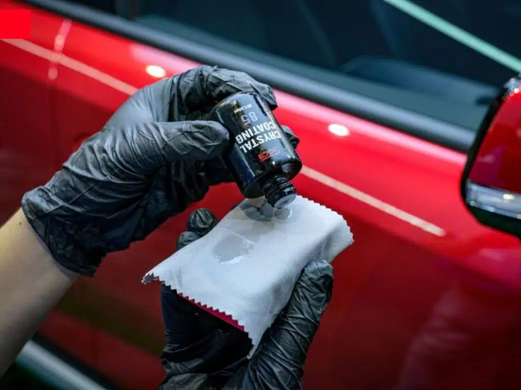 Kỹ thuật viên trung tâm chăm sóc xe hơi đang thực hiện phủ ceramic bảo vệ sơn xe bằng dung dịch chuyên dụng.