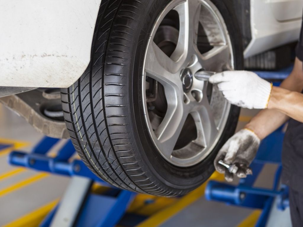 Thợ đang siết ốc bánh xe trong quy trình vá lốp ô tô tại nhà chuyên nghiệp.