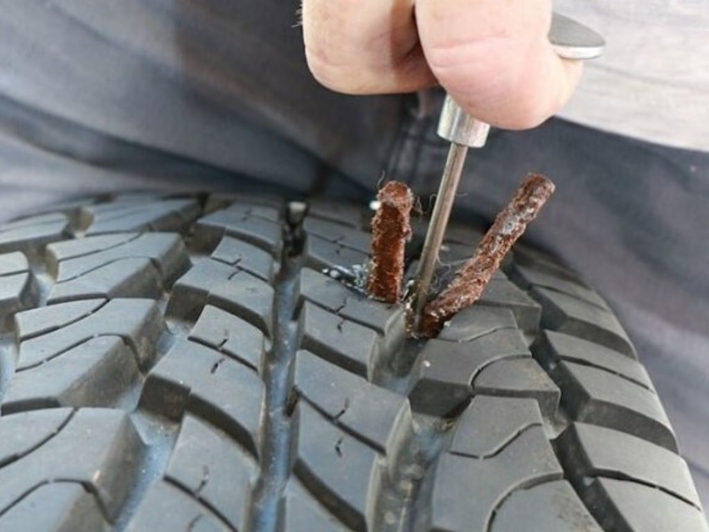 Thợ dùng bộ dụng cụ chuyên dụng vá lốp ô tô tại nhà với miếng vá bằng keo cao su.