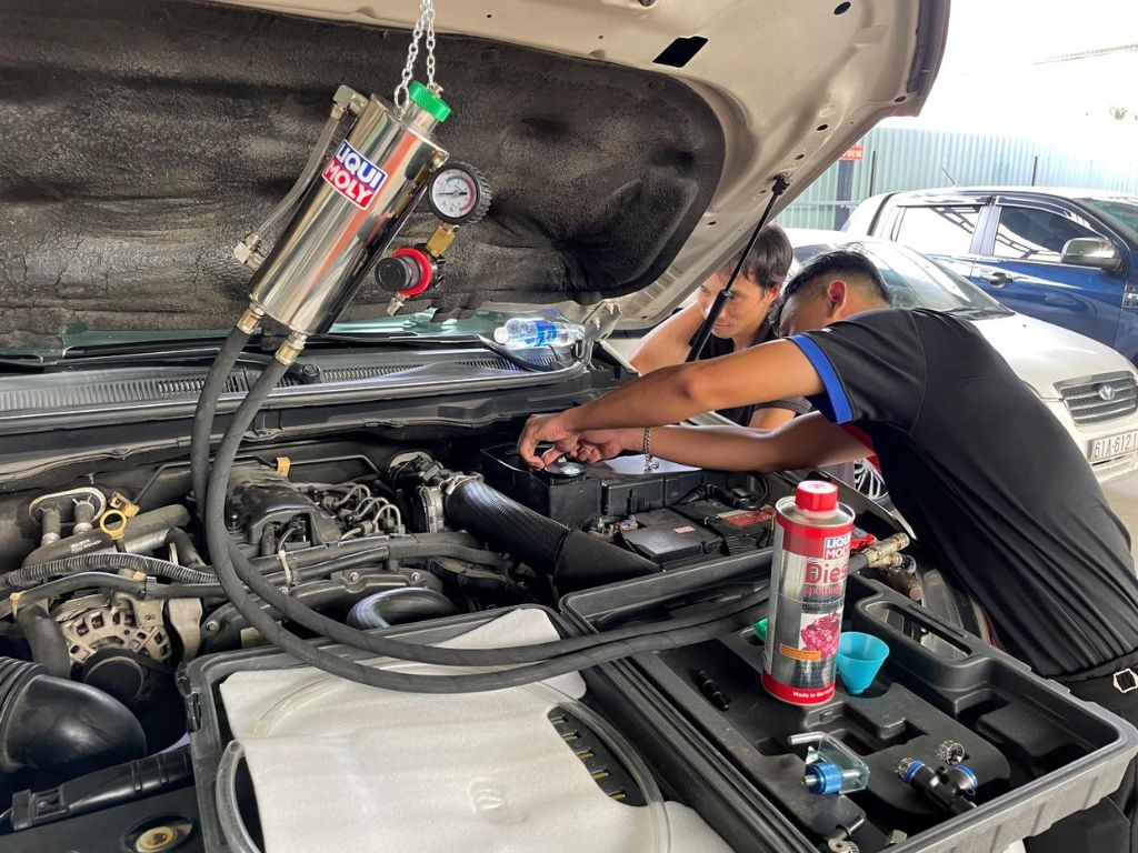 Kỹ thuật viên đang vệ sinh buồng đốt ô tô bằng dung dịch Liqui Moly chuyên dụng tại gara, giúp loại bỏ muội than và cải thiện hiệu suất động cơ.