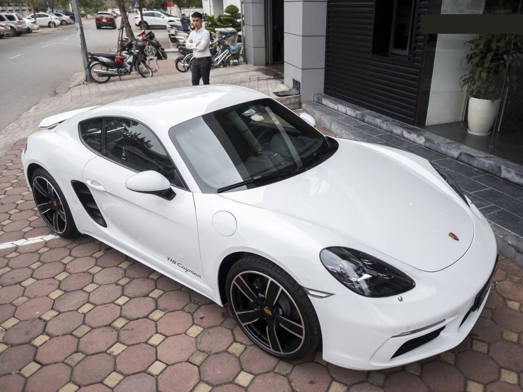 Porsche 718 Cayman trắng đỗ trước showroom – xe hơi 2 chỗ thể thao cao cấp dành cho người yêu tốc độ.