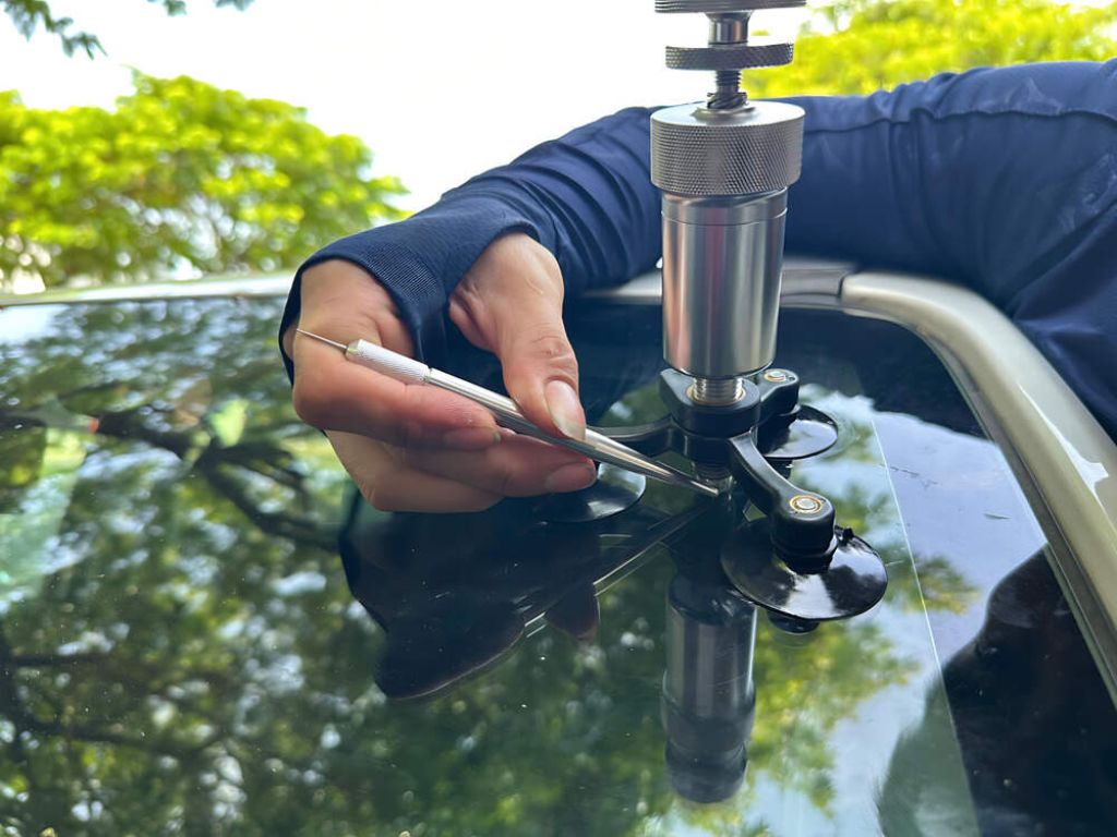Kỹ thuật viên xử lý vết nứt trên kính ô tô bằng dụng cụ ép keo chuyên nghiệp