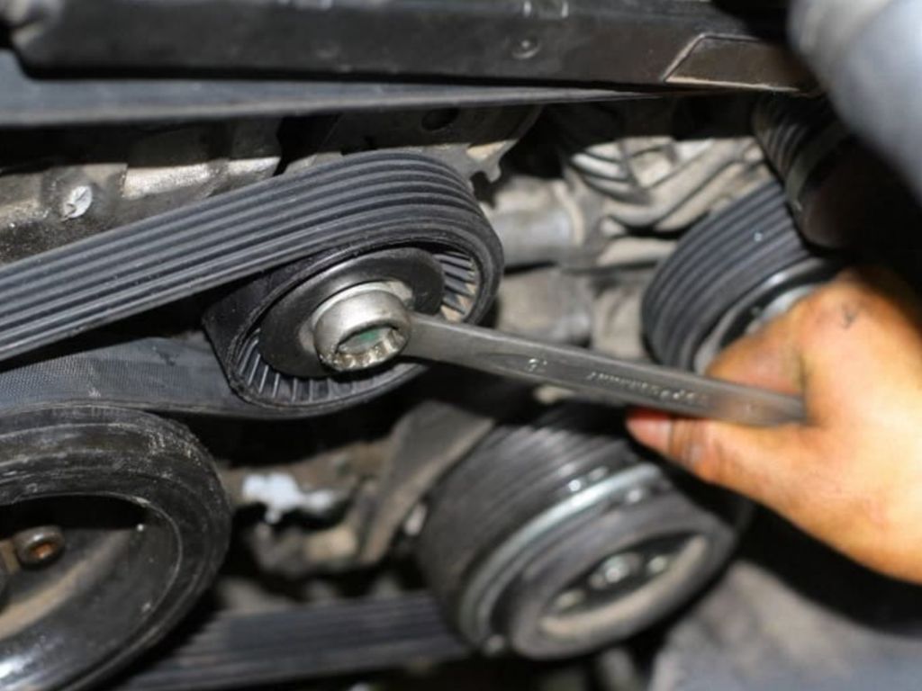 Thợ đang kiểm tra và siết lại dây curoa ô tô bị trùng bằng cờ lê để đảm bảo độ căng tiêu chuẩn.