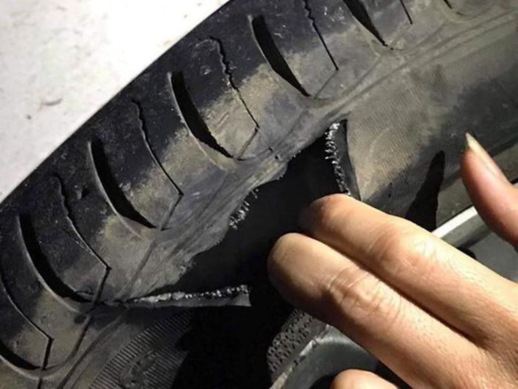 Lốp ô tô bị sứt rách lớn ở hông do va phải vật nhọn, tiềm ẩn nguy cơ nổ lốp khi di chuyển tốc độ cao.