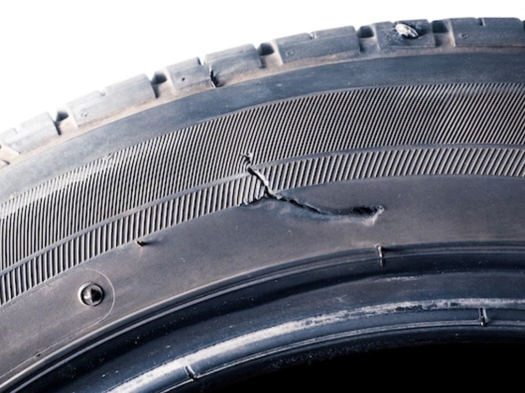 Lốp ô tô bị sứt bên hông do va quẹt lề đường, bề mặt cao su bong tróc cần thay gấp để đảm bảo an toàn