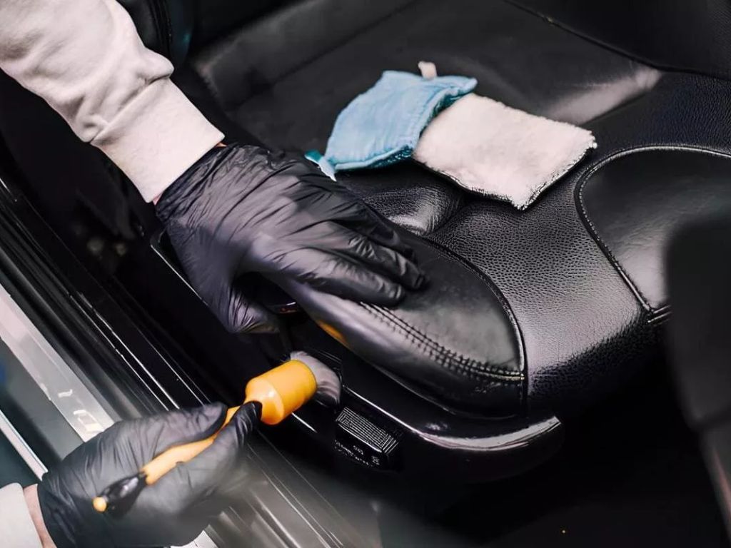 Thợ dùng cọ mềm và khăn lau vệ sinh ghế da màu đen – vệ sinh ghế da ô tô đúng cách giúp da mềm mịn và bền màu.
