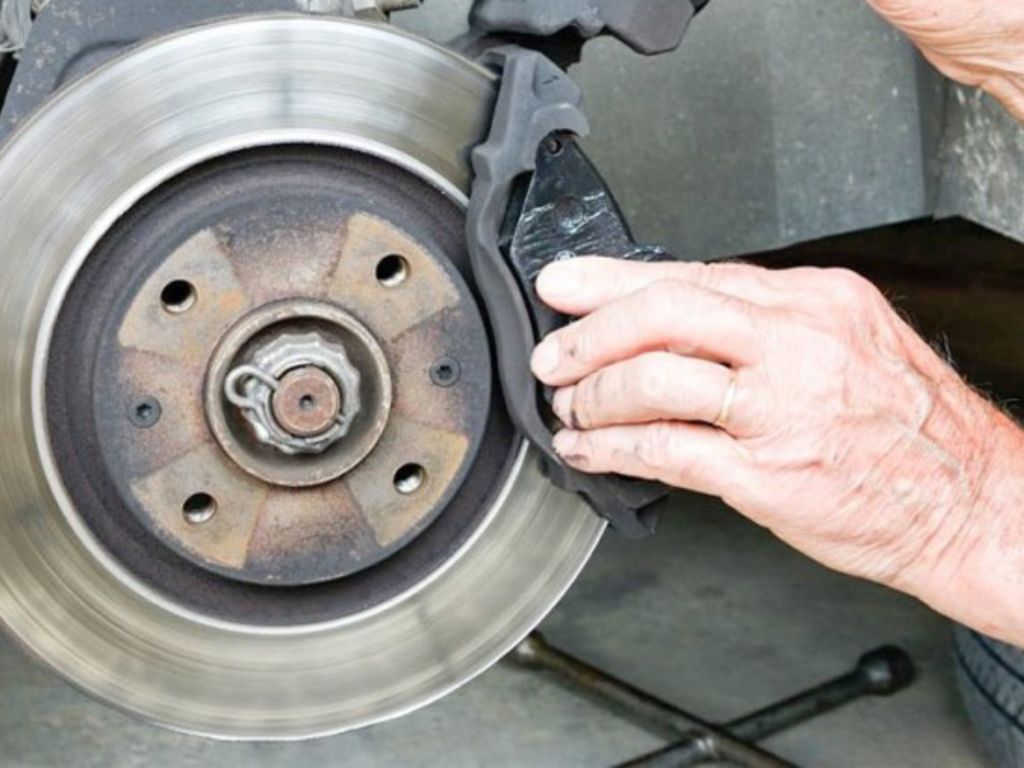 Thợ đang thay bố thắng ô tô – xử lý tình trạng xe ô tô bị bó thắng do má phanh mòn không đều.