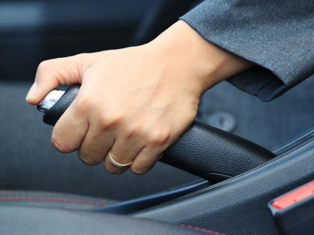 Kéo phanh tay trong xe – minh họa nguyên nhân xe ô tô bị bó thắng do phanh tay kẹt.