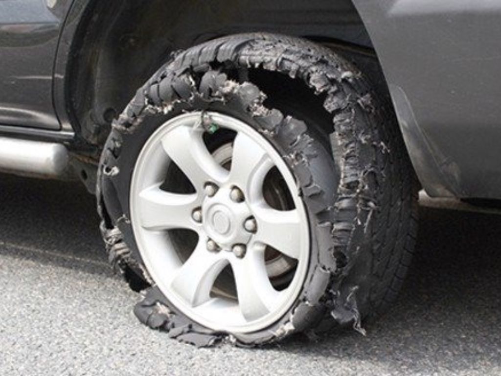 Xe ô tô bị nổ lốp nghiêm trọng khiến phần vỏ lốp bung ra khỏi vành bánh xe trên đường.