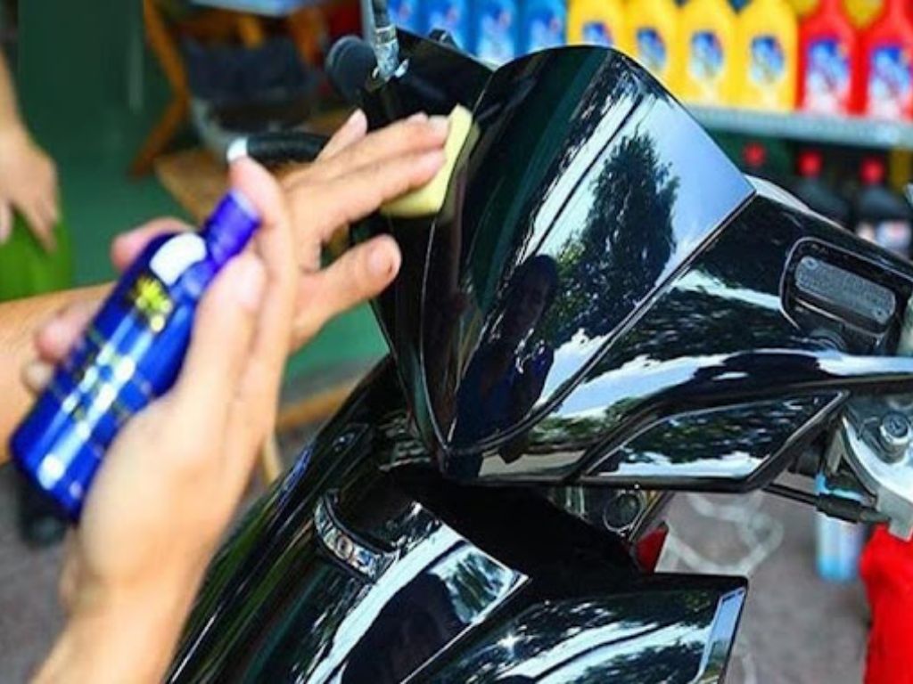 Thợ đang phủ ceramic xe máy lên dàn nhựa để tạo độ bóng và bảo vệ bề mặt.